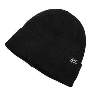 Vue détaillée de la maille côtelée noire et du logo H+D sur un bonnet d'hiver chaud