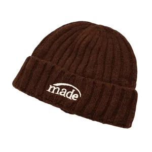 Detail der 'made' Stickerei auf dunkelbrauner Strickmütze mit grober Rippenstruktur