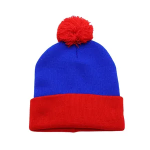 Detail view of the red and blue knit beanie texture with a fluffy pompom top