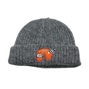 Detail of dark grey ribbed knit beanie featuring orange cartoon patch and COOL embroidery