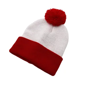 Detail view of two-tone knit beanie with red pom-pom and thick ribbed texture