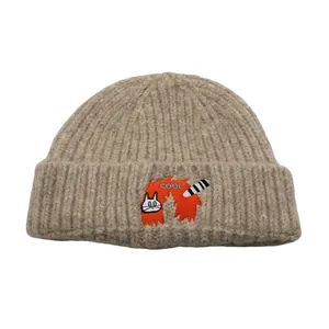 Detailed view of the cute cat embroidery and COOL text on the beige knitted beanie
