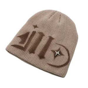 Detail of beige knit beanie featuring hand-painted brown letters and a silver star charm