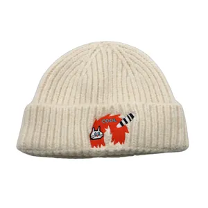 Detailed close-up of cream beanie featuring COOL text and cute cat embroidery