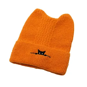 Macro detail of cat ear beanie featuring vibrant orange knit and cute kitten embroidery