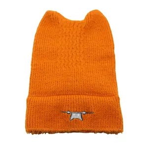 Detail of orange knit beanie with cat ears and small monster embroidery on the cuff