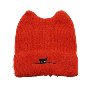 Detail of red knitted beanie with cat ears and minimalist black cat embroidery detail