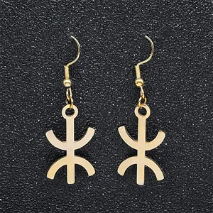 Macro detail of gold Berber Yaz symbol earrings on a textured black backdrop