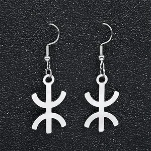 Detailed view of silver stainless steel Berber Yaz symbol drop earrings on dark background