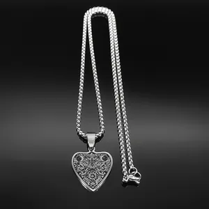 Macro shot of heart-shaped stainless steel pendant with intricate vine patterns and eye detail
