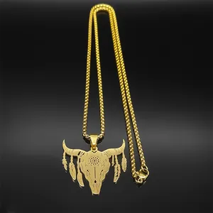 Macro shot of golden bull skull pendant with sun totem and feather charms on mirror base