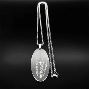 Macro shot of silver stainless steel oval pendant with engraved Lord’s Prayer and cross