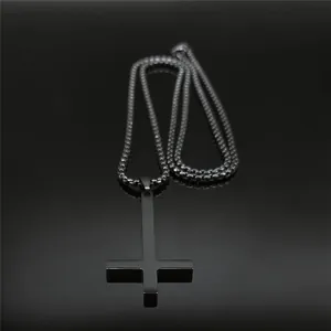 Détail du pendentif croix inversée noire avec chaîne à billes sur surface réfléchissante