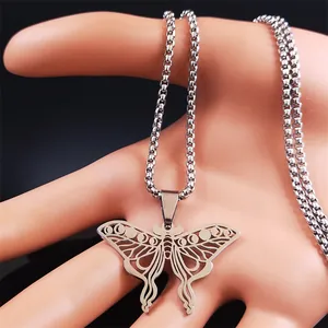 Vue macro d'un collier papillon argenté évidé avec phases de lune tenu à la main
