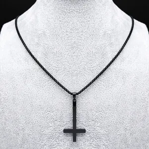 Gros plan d'un pendentif croix inversée noir mat sur un buste de bijoux gris texturé