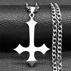 Macro shot of silver inverted cross pendant with cuban chain on black leather background