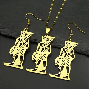 Detailed set of gold Pharaoh pendant necklace and drop earrings on black stone surface