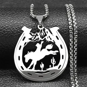 Macro shot of a silver horseshoe pendant featuring a cowboy silhouette and mountain scenery