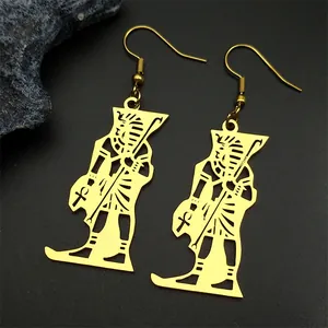 Detail of gold Egyptian Pharaoh and Ankh symbol drop earrings on a black stone surface