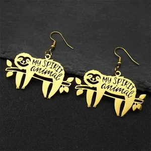 Detail of golden sloth earrings with MY SPIRIT animal text on black stone background