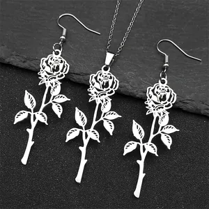 Dettaglio del set collana e orecchini a forma di rosa in acciaio su sfondo di pietra scura