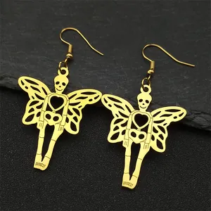 Golden skeleton butterfly wing earrings with heart cutout on dark stone background