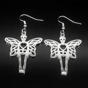 Macro detail of silver gothic skull heart earrings with wings on black reflective surface