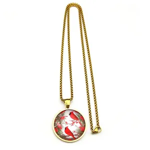 Detailed close-up of a golden necklace with a glass pendant featuring two red cardinals
