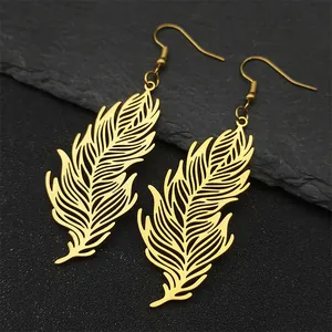 Detail of golden hollow feather earrings showing fine craftsmanship on stone background