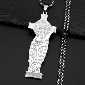 Detail of St. Benedict silver cross pendant with intricate engraving on a dark stone background