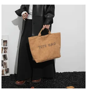 Detail of tan tote bag with perforated TOTE BAG text in a modern studio setting