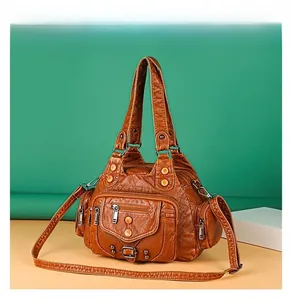 Dettaglio borsa a tracolla in pelle color caramello con tasche multiple e cerniere