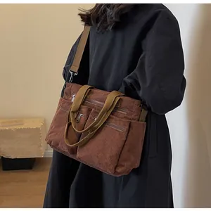 Brown corduroy tote bag detail showing dual front zipper pockets and adjustable strap
