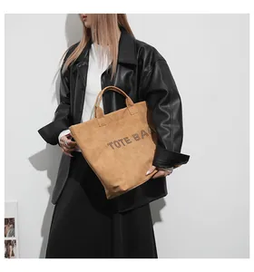 Detail of light brown suede tote bag featuring modern dotted TOTE BAG lettering print
