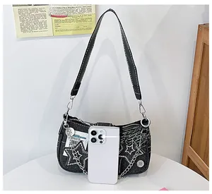 Détail du sac épaule Y2K en jean avec étoiles, chaînes et comparaison de taille au mobile