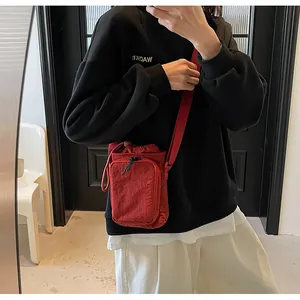 Detailansicht einer roten Nylon-Umhängetasche mit Kordelzug und breitem Schultergurt
