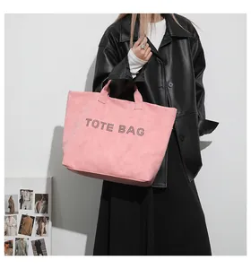 Close-up of pink tote bag with rhinestone TOTE BAG lettering and matte suede texture