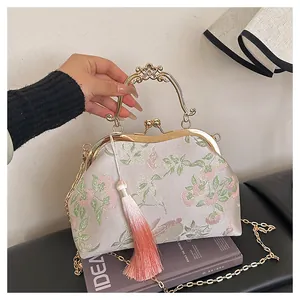 Vue détaillée du sac vintage brodé avec poignée dorée sculptée et pompon décoratif