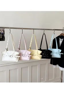 Cinq sacs cabas en cuir ciré plissé de différentes couleurs suspendus sur un support métal