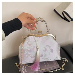 Détail de la broderie florale sur soie lavande et fermoir doré avec pompon violet