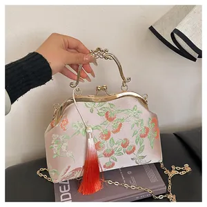 Détail d'un sac brodé de style chinois avec motifs floraux et pompon en soie