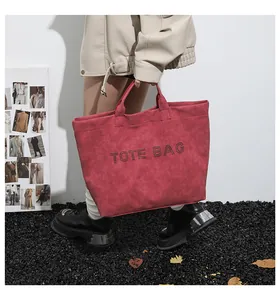 Detail of red oversized tote bag in matte suede with metallic TOTE BAG lettering