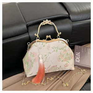 Détail d'un sac brodé vintage avec poignée dorée en forme de fleur et gland soyeux