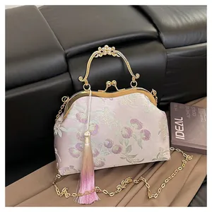 Détail de broderie florale sur sac jacquard vintage avec fermoir doré et gland en soie