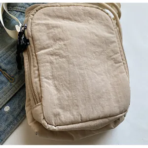 Detailansicht der beigen Nylon-Umhängetasche mit Doppelreißverschluss auf Jeansstoff