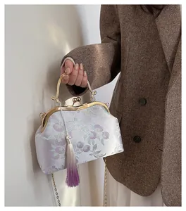Détail de broderie florale sur pochette en soie lavande avec élégant pompon violet