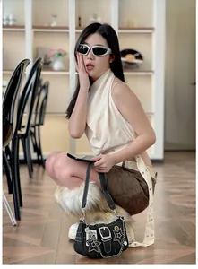 Détail d'un sac à épaule Y2K en denim noir avec patchs d'étoiles et chaînes argentées