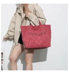 Detail of the oversized dark red tote bag featuring embossed TOTE BAG lettering and texture