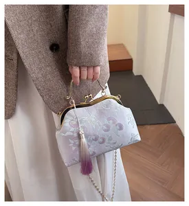 Détail de broderie lavande sur sac rétro à fermoir avec anse dorée et pompon décoratif