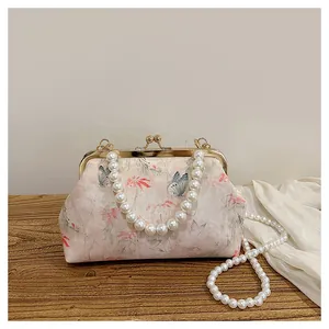 Macro view of vintage floral fabric and elegant pearl chain handle on a kiss-lock bag